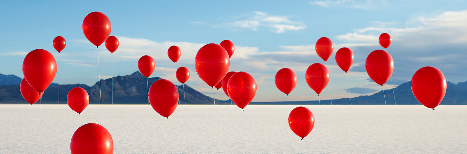 Røde ballonger med landskap i bakgrunnen